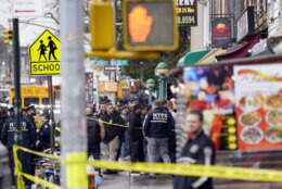 New York City Police Department personnel gather at the entrance to a subway stop in the Brooklyn borough of New York, Tuesday, April 12, 2022. Five people were shot Tuesday morning at a subway station in Brooklyn, New York, law enforcement sources said. (AP Photo/John Minchillo)
