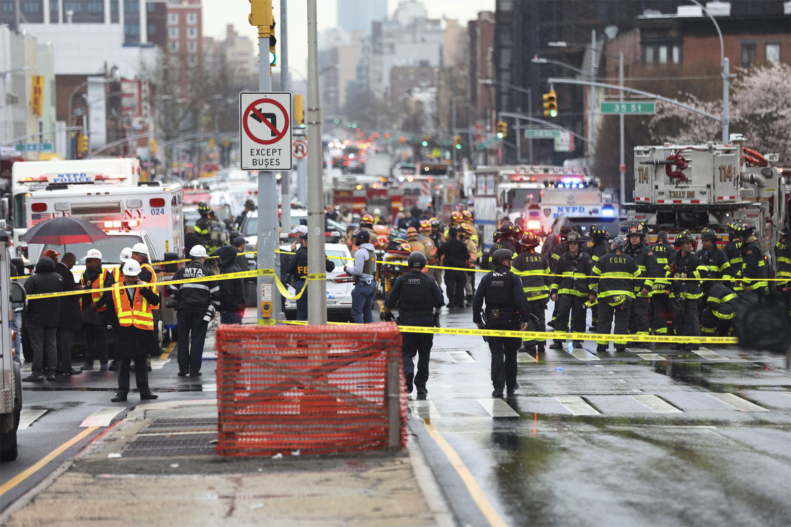 Law enforcement gather near the entrance to a subway stop in the Brooklyn borough of New York, Tuesday, April 12, 2022.  Multiple people were shot and injured Tuesday at a subway station in New York City during a morning rush hour attack that left wounded commuters bleeding on a train platform.. (AP Photo/Kevin Hagen).