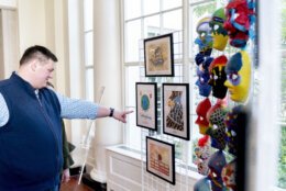 A visitor looks at artwork by military connected children on display along the public tour route at the White House in Washington, Friday, April 29, 2022, First lady Jill Biden has added a temporary installation in the East Wing of more then 20 pieces of artwork from military children across the country and those stationed around the world.in honor of the Month of the Military Child. (AP Photo/Andrew Harnik)