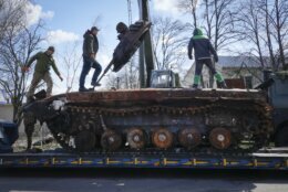 Road workers load a destroyed Russian tank onto a platform in the village of Andriyivka close to Kyiv, Ukraine, Monday, April 11, 2022. Andriyivka was occupied by the Russian troops at the beginning of the Russia-Ukraine war and freed recently by the Ukrainian army. (AP Photo/Efrem Lukatsky)