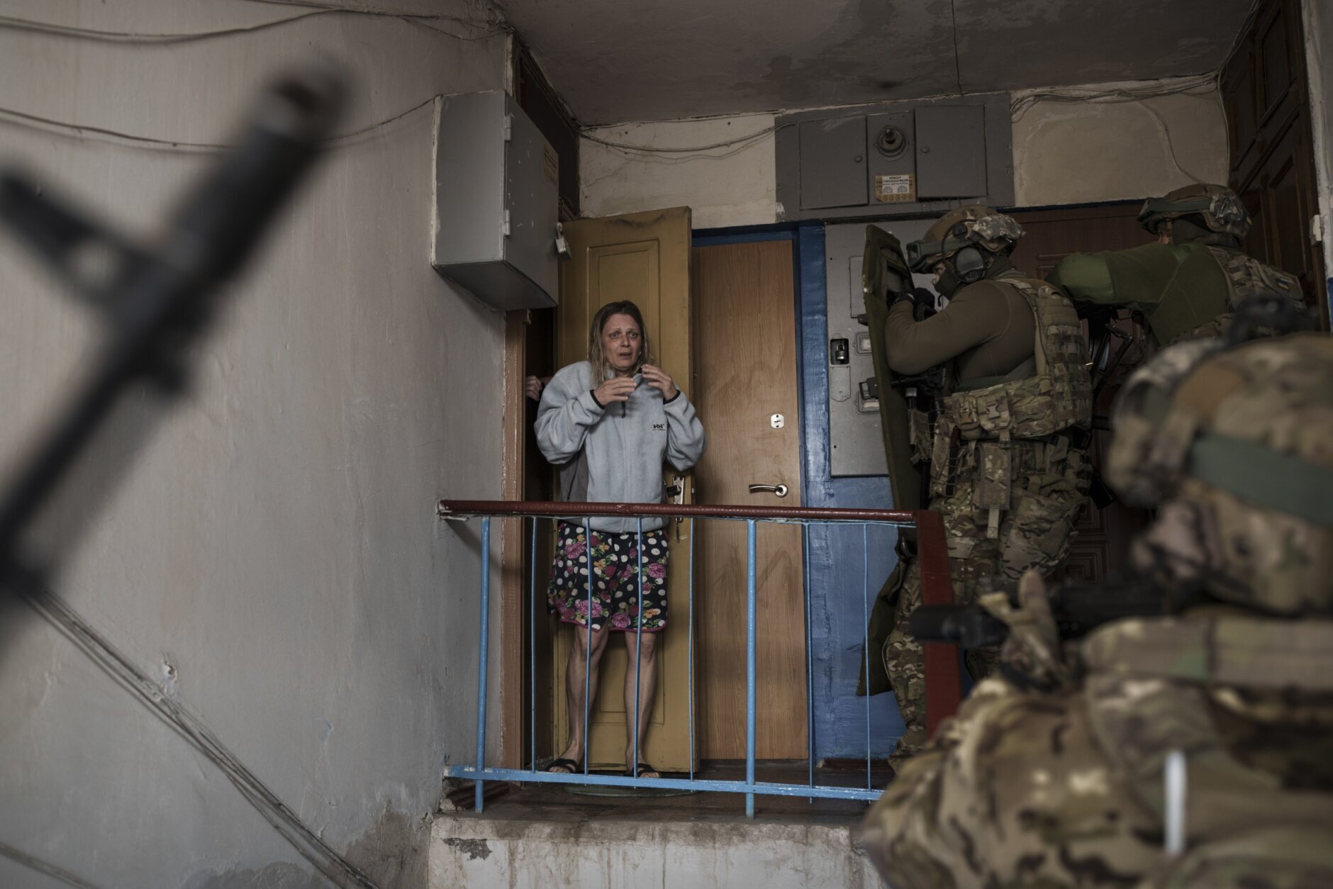 A woman looks as Security Service of Ukraine (SBU) servicemen enter a building during an operation to arrest suspected Russian collaborators in Kharkiv, Ukraine, Thursday, April 14, 2022. (AP Photo/Felipe Dana)