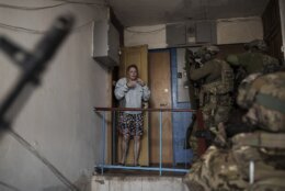 A woman looks as Security Service of Ukraine (SBU) servicemen enter a building during an operation to arrest suspected Russian collaborators in Kharkiv, Ukraine, Thursday, April 14, 2022. (AP Photo/Felipe Dana)