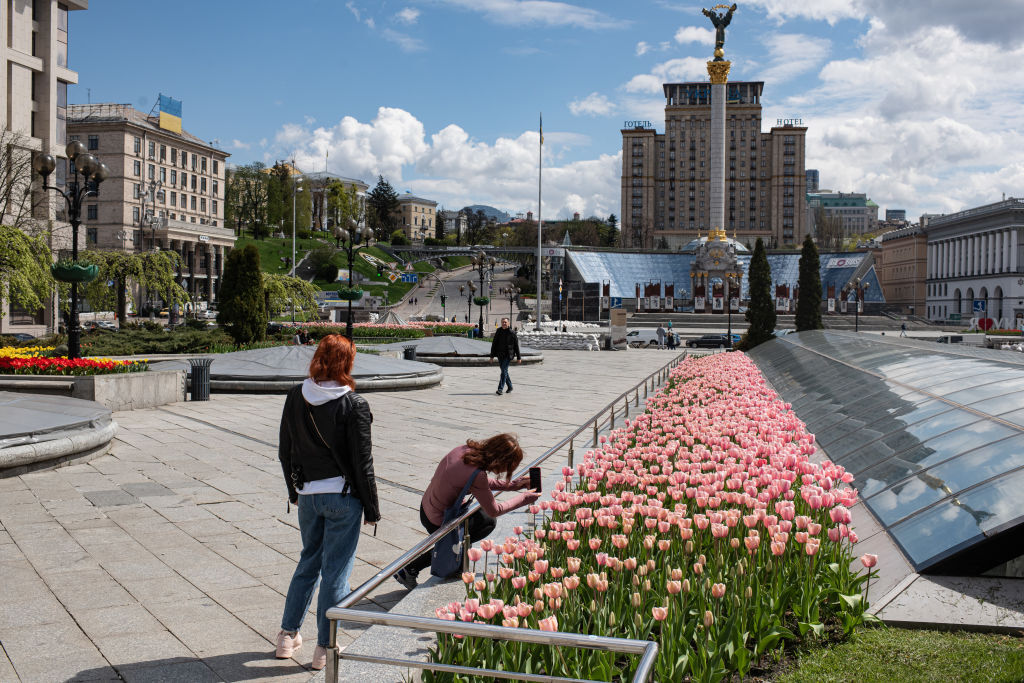 KYIV, UKRAINE - APRIL 27: Young woman takes a photo of tulips in blossom on Independence Square on April 27, 2022 in Kyiv, Ukraine. Following Russia's retreat from areas around the Ukrainian capital, signs of normal life have returned to Kyiv, with residents taking advantage of shortened curfew hours, businesses reopening, and foreign countries promising to return their diplomats. (Photo by Alexey Furman/Getty Images)