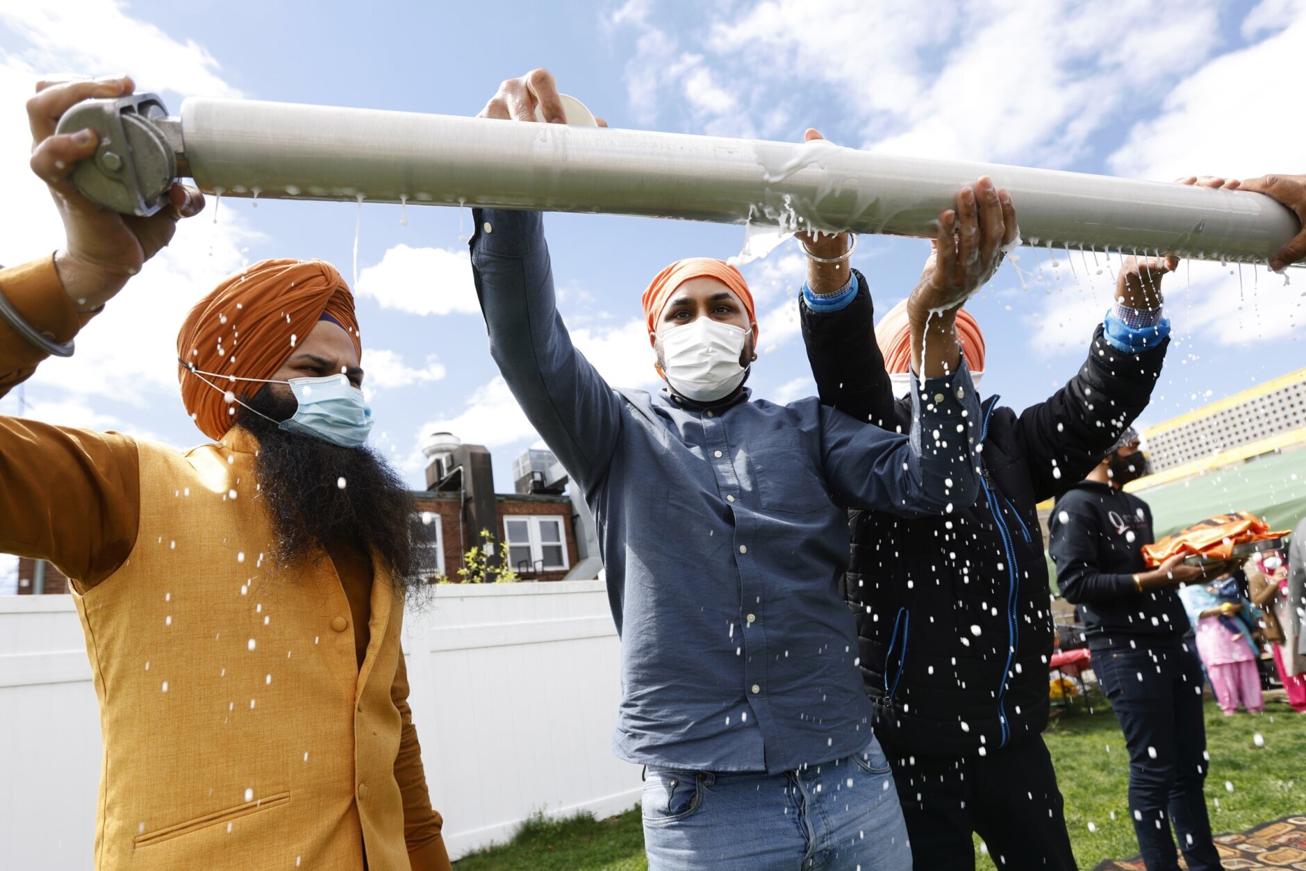 FILE - Jasbir Singh, left, and Vijay Singh wash a flagpole with milk as part of a ceremonial changing of the Sikh flag during Vaisakhi celebrations at Guru Nanak Darbar of Long Island, Tuesday, April 13, 2021 in Hicksville, N.Y. In a convergence that happens only rarely, Judaism’s Passover, Christianity’s Easter and Islam’s holy month of Ramadan are interlapping in April with holy days for Buddhists, Baha’is, Sikhs, Jains and Hindus, offering different faith groups a chance to share meals and rituals in a range of interfaith events. (AP Photo/Jason DeCrow, File)