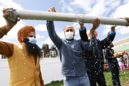 FILE - Jasbir Singh, left, and Vijay Singh wash a flagpole with milk as part of a ceremonial changing of the Sikh flag during Vaisakhi celebrations at Guru Nanak Darbar of Long Island, Tuesday, April 13, 2021 in Hicksville, N.Y. In a convergence that happens only rarely, Judaism’s Passover, Christianity’s Easter and Islam’s holy month of Ramadan are interlapping in April with holy days for Buddhists, Baha’is, Sikhs, Jains and Hindus, offering different faith groups a chance to share meals and rituals in a range of interfaith events. (AP Photo/Jason DeCrow, File)