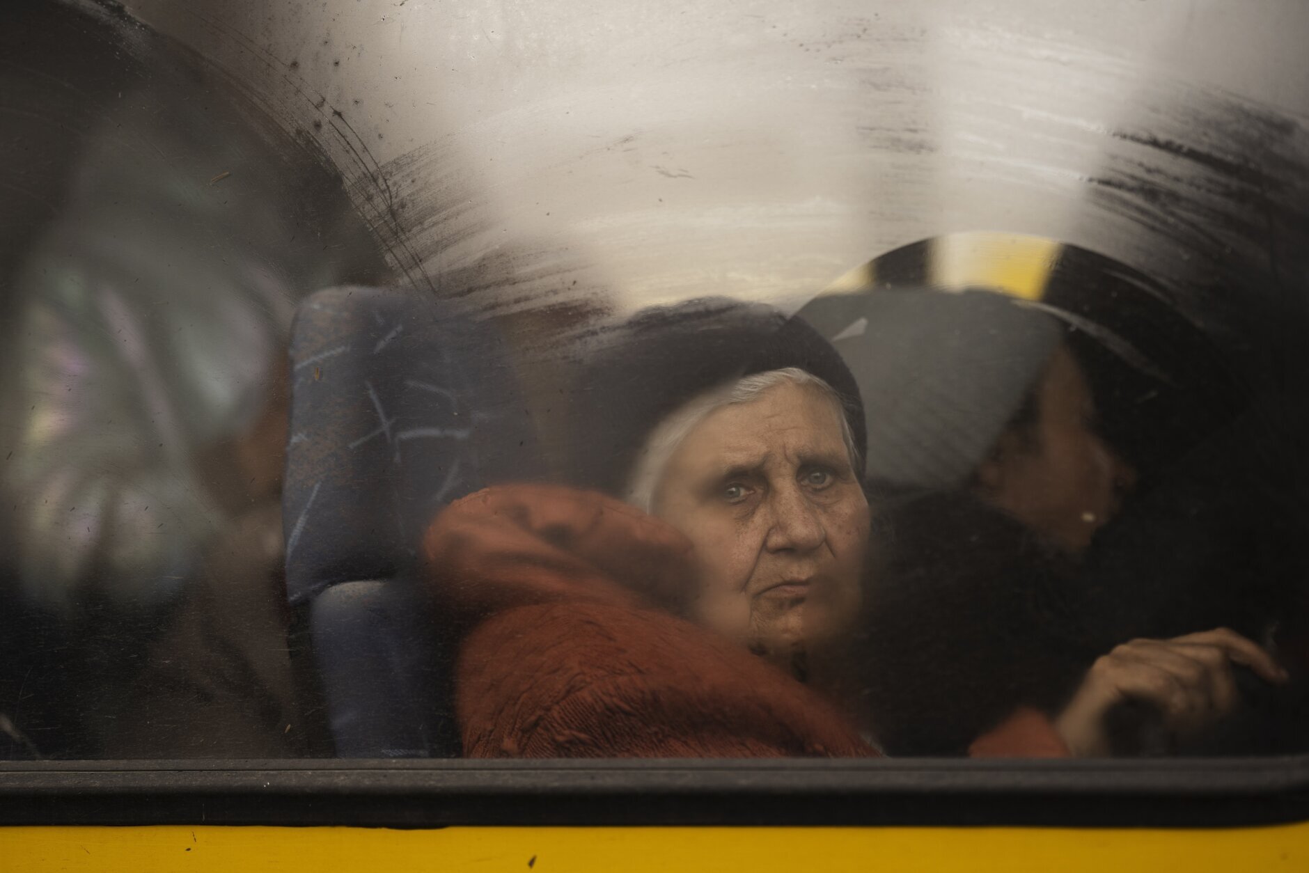 An internally displaced elderly woman from Mariupol looks out of a bus after window arriving at a refugee center fleeing from the Russian attacks, in Zaporizhzhia, Ukraine, Thursday, April 21, 2022. Mariupol, which is part of the industrial region in eastern Ukraine known as the Donbas, has been a key Russian objective since the Feb. 24 invasion began. (AP Photo/Leo Correa)