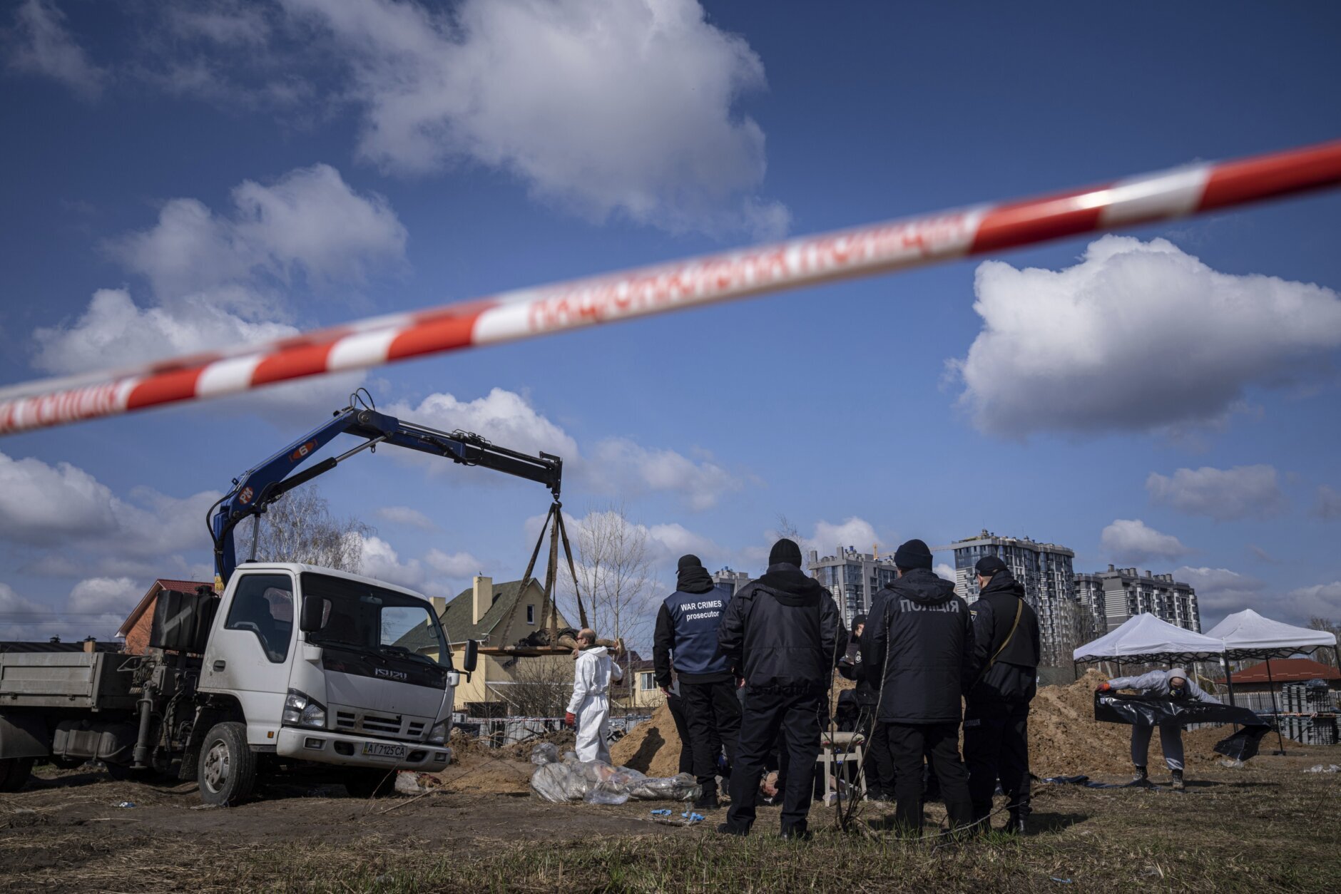 Forensic scientists and police inspect dead bodies of local residents after removing them from a mass grave in Bucha, on the outskirts of Kyiv, Ukraine, Monday, April 11, 2022. (AP Photo/Evgeniy Maloletka)