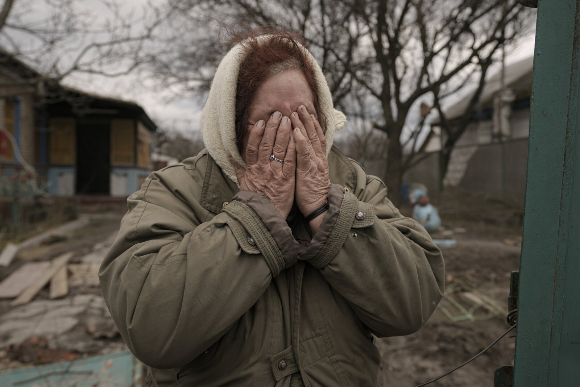 Tetiana Oleksiienko cries standing at the gate of her house in the village of Andriivka, Ukraine, heavily affected by fighting between Russian and Ukrainian forces, Wednesday, April 6, 2022. Several buildings in the village were reduced to mounds of bricks and corrugated metal and residents struggle without heat, electricity or cooking gas. (AP Photo/Vadim Ghirda)