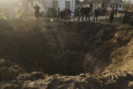 People look at a crater of an explosion in a village of Horodnya, Chernihiv region, Ukraine, Thursday, April 14, 2022. (AP Photo/George Ivanchenko)