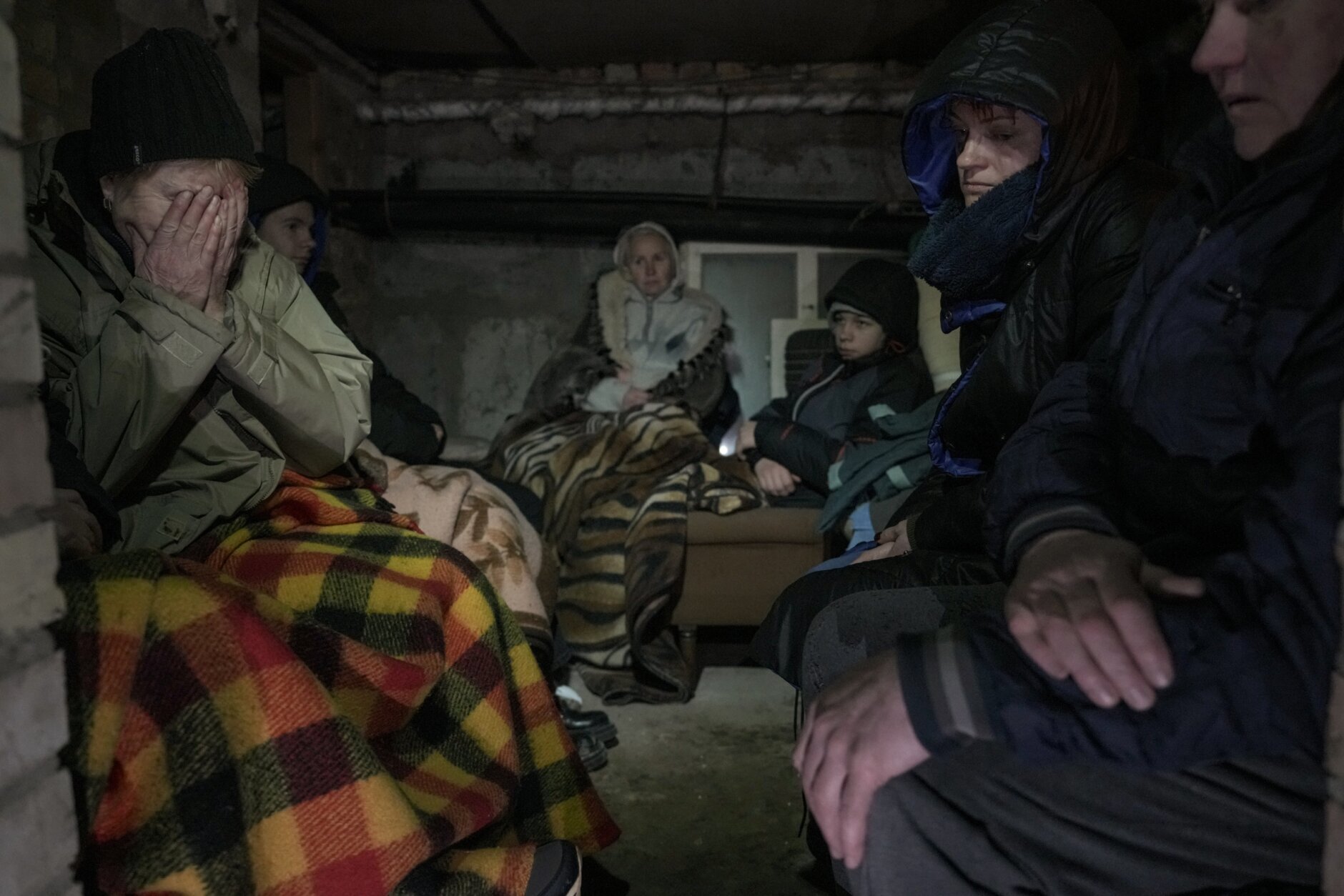 A woman cries in the small basement of a house crowded with people seeking shelter from Russian airstrikes and shelling in Gorenka, outside the capital Kyiv, Ukraine, Wednesday, March 2, 2022. (AP Photo/Vadim Ghirda)