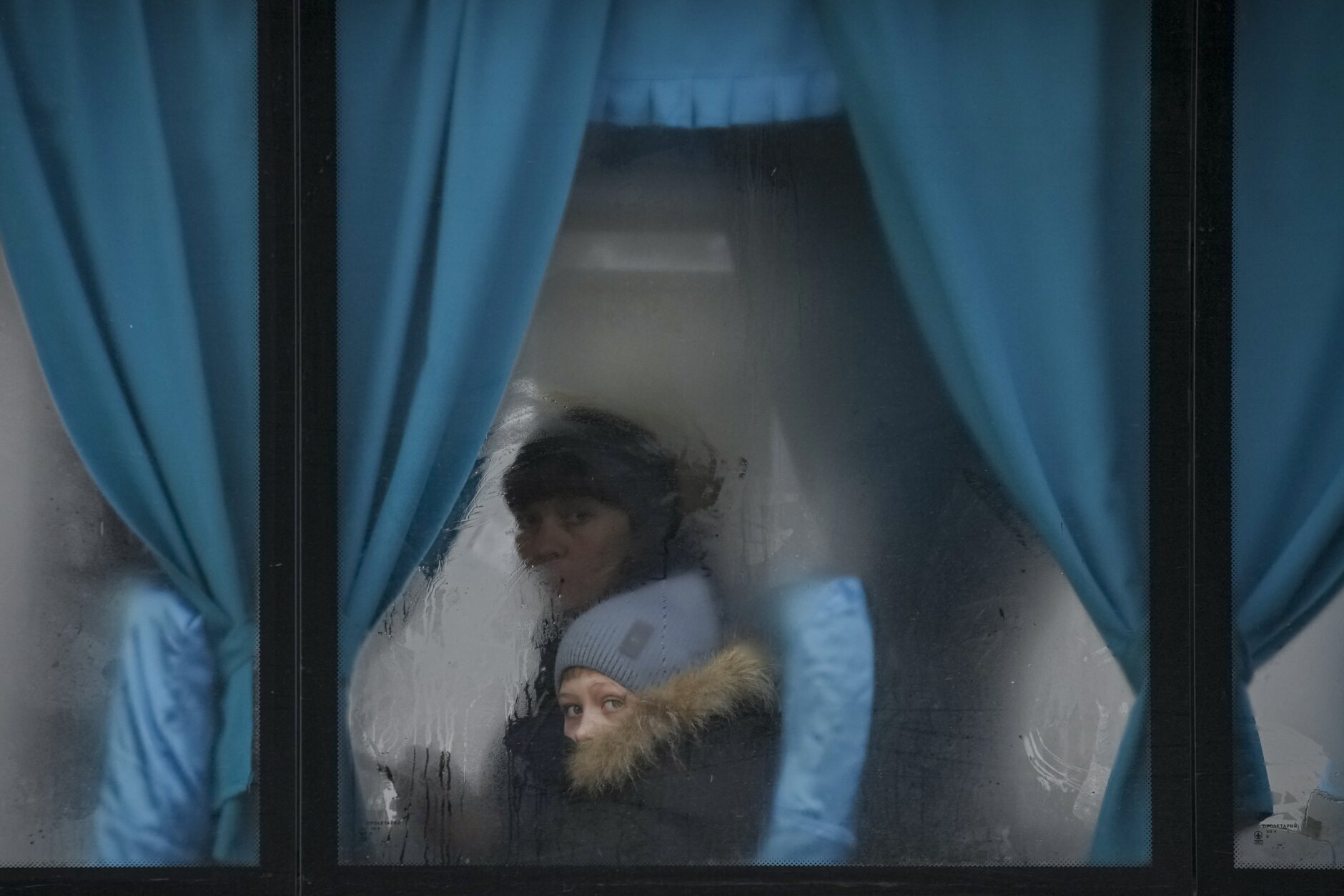 A woman and child peer out of the window of a bus as they leave Sievierodonetsk, the Luhansk region, in eastern Ukraine, Thursday, Feb. 24, 2022. (AP Photo/Vadim Ghirda)