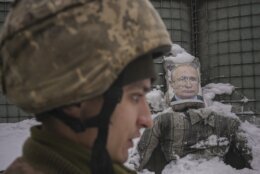 A Ukrainian serviceman speaks, backdropped by a bullet riddled effigy of Russian President Vladimir Putin, during a media interview at a frontline position in the Luhansk region, eastern Ukraine, Tuesday, Feb. 1, 2022. (AP Photo/Vadim Ghirda)