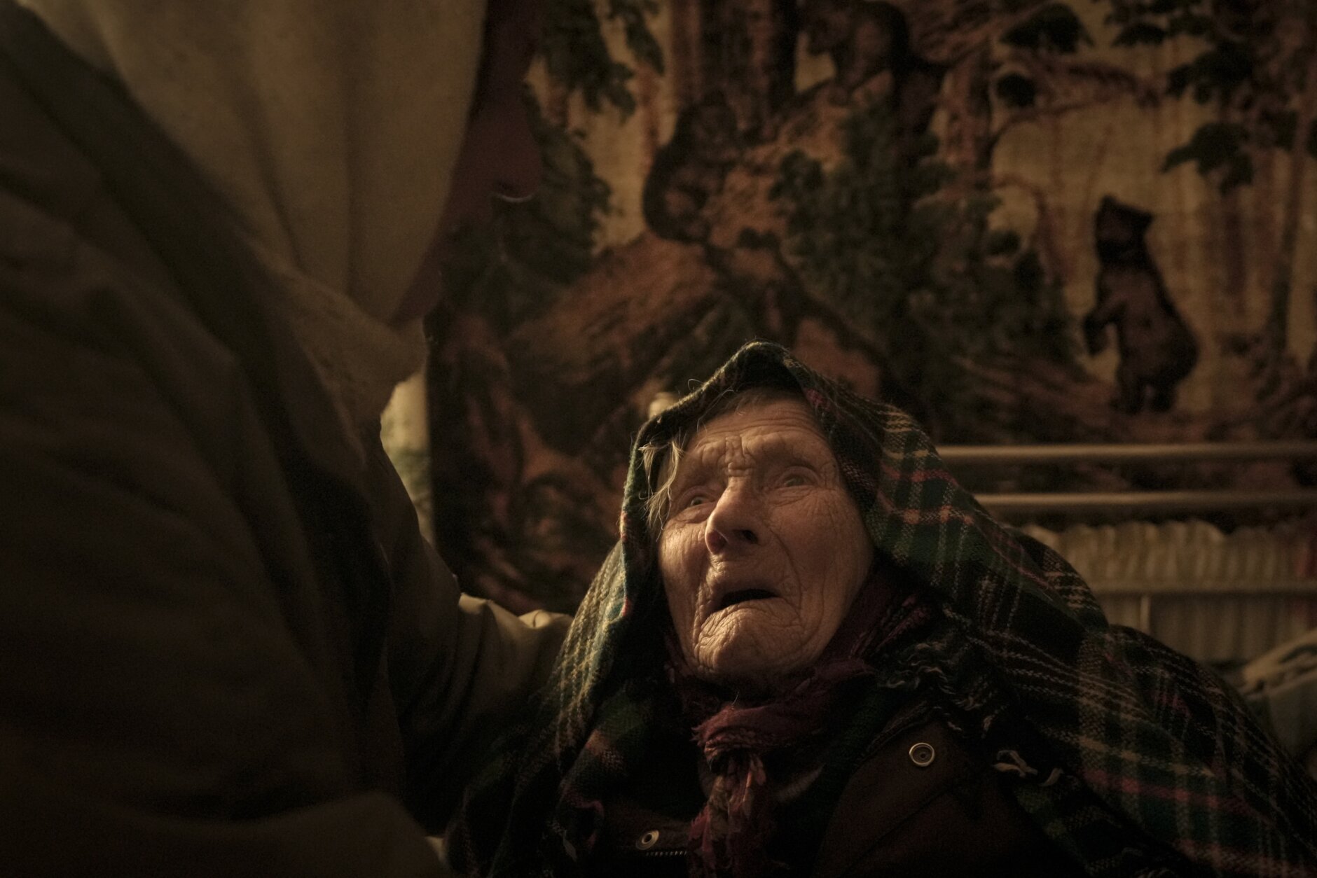 Motria Oleksiienko, 99, traumatized by the Russian occupation, is comforted by Tetiana Oleksiienko in a room without heating in the village of Andriivka, Ukraine, heavily affected by fighting between Russian and Ukrainian forces, Wednesday, April 6, 2022. Several buildings in the village were reduced to mounds of bricks and corrugated metal and residents struggle without heat, electricity or cooking gas. (AP Photo/Vadim Ghirda)