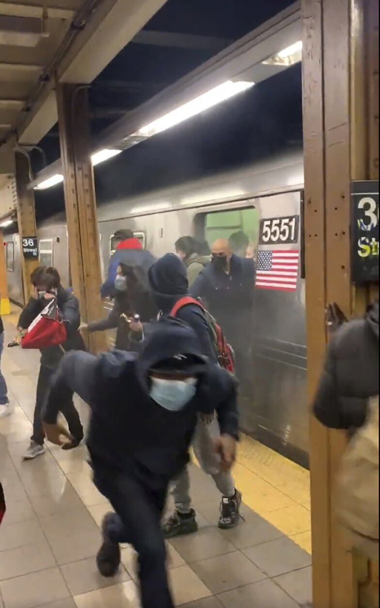 In this photo from social media video, passengers run from a subway car in a station in the Brooklyn borough of New York, Tuesday, April 12, 2022. A gunman filled a rush-hour subway train with smoke and shot multiple people Tuesday, leaving wounded commuters bleeding on a Brooklyn platform as others ran screaming, authorities said. Police were still searching for the suspect. (Will B Wylde via AP) (Will B. Wylde via AP)