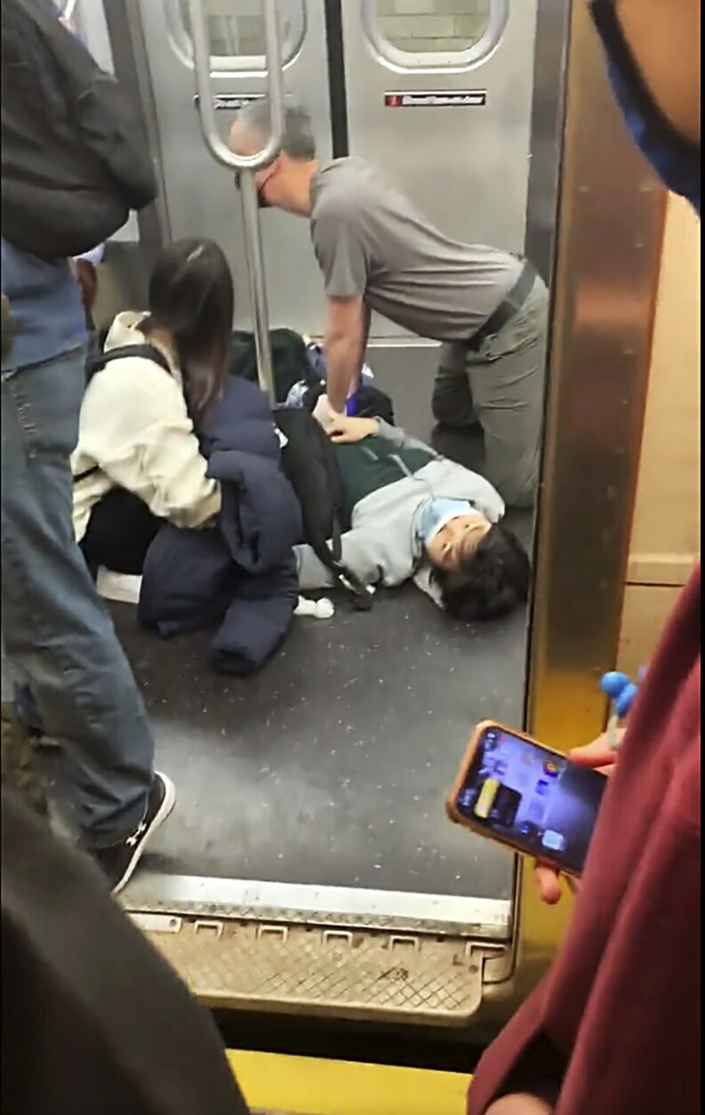 This photo provided by Will B Wylde,  a person is aided in a subway car in the Brooklyn borough of New York, Tuesday, April 12, 2022. A gunman filled a rush-hour subway train with smoke and shot multiple people Tuesday, leaving wounded commuters bleeding on a Brooklyn platform as others ran screaming, authorities said. Police were still searching for the suspect. (Will B Wylde via AP)