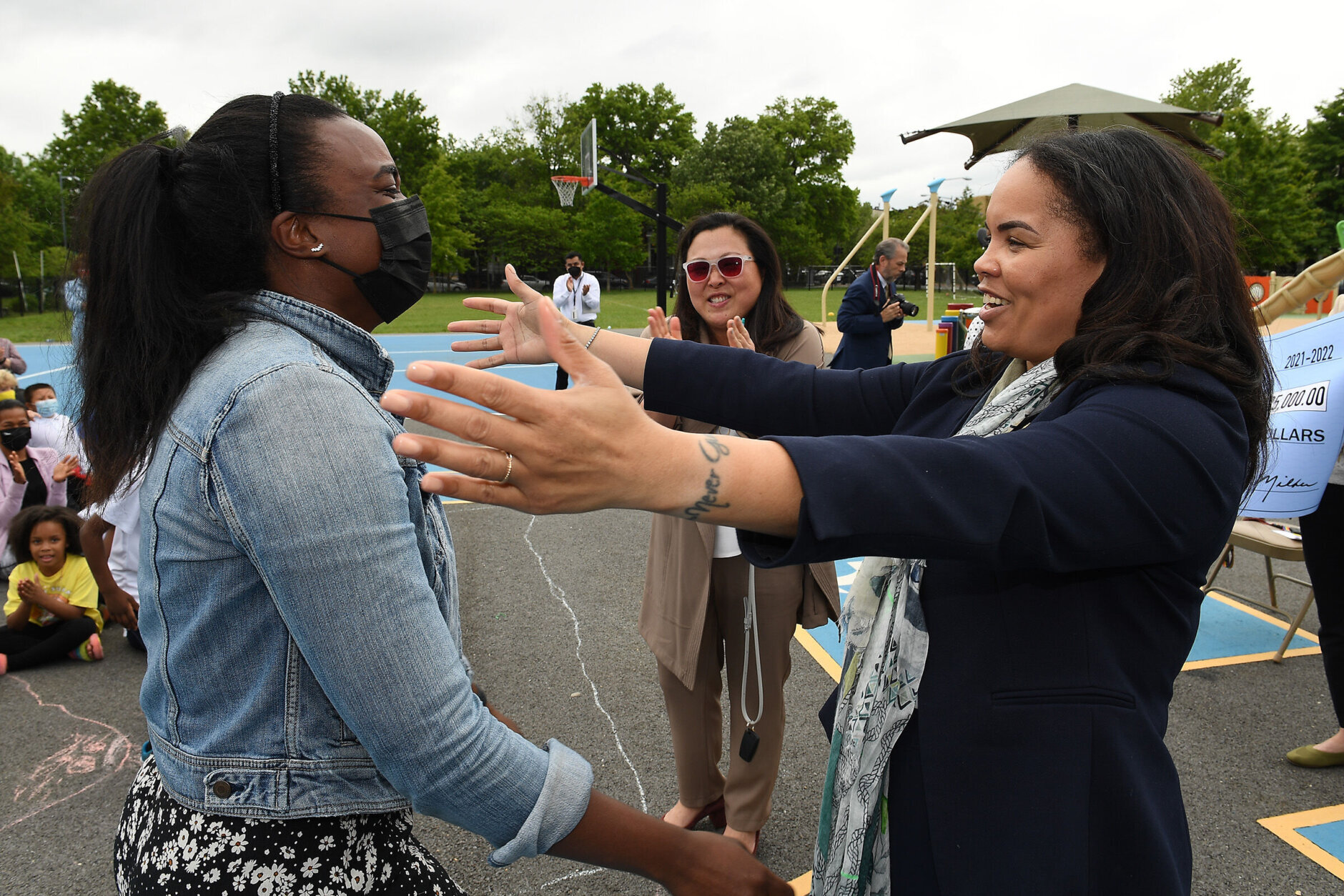 While DC Public Schools Deputy Chancellor Dr.  Melissa Kim looks on, Washington DC Superintendent of Education congratulates Dr.  Christina Grant Jenelle Bryant with her Milken Educator Award. 