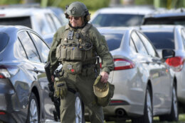 A tactical police officer walks near where a man opened fire at a business, killing three people before the suspect and a state trooper were wounded in a shootout, according to authorities, in Smithsburg, Md., Thursday, June 9, 2022. The Washington County (Md.) Sheriff's Office said in a news release that three victims were found dead at Columbia Machine Inc. and a fourth victim was critically injured. (AP Photo/Steve Ruark)