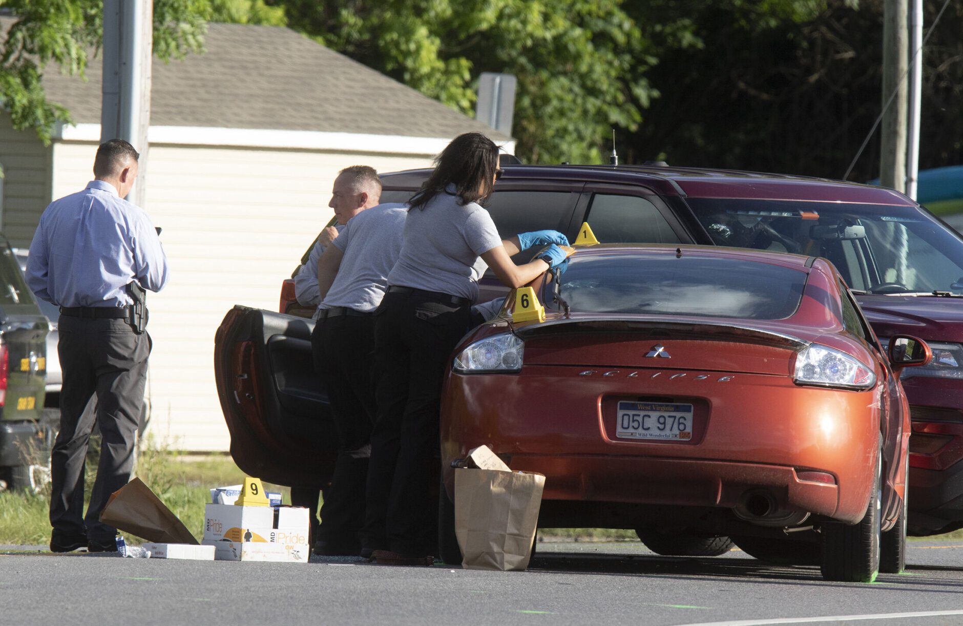 Law enforcement officials process evidence from one of two cars that were involved in a shooting involving a Maryland State Police officer on Thursday, June 9, 2022 along Mt. Aetna Road near Smithsburg, Md. An employee opened fire at a manufacturing business in rural western Maryland on Thursday, killing three coworkers before the suspect and a state trooper were wounded in a shootout, authorities said.  (AP Photo/Timothy Jacobsen)