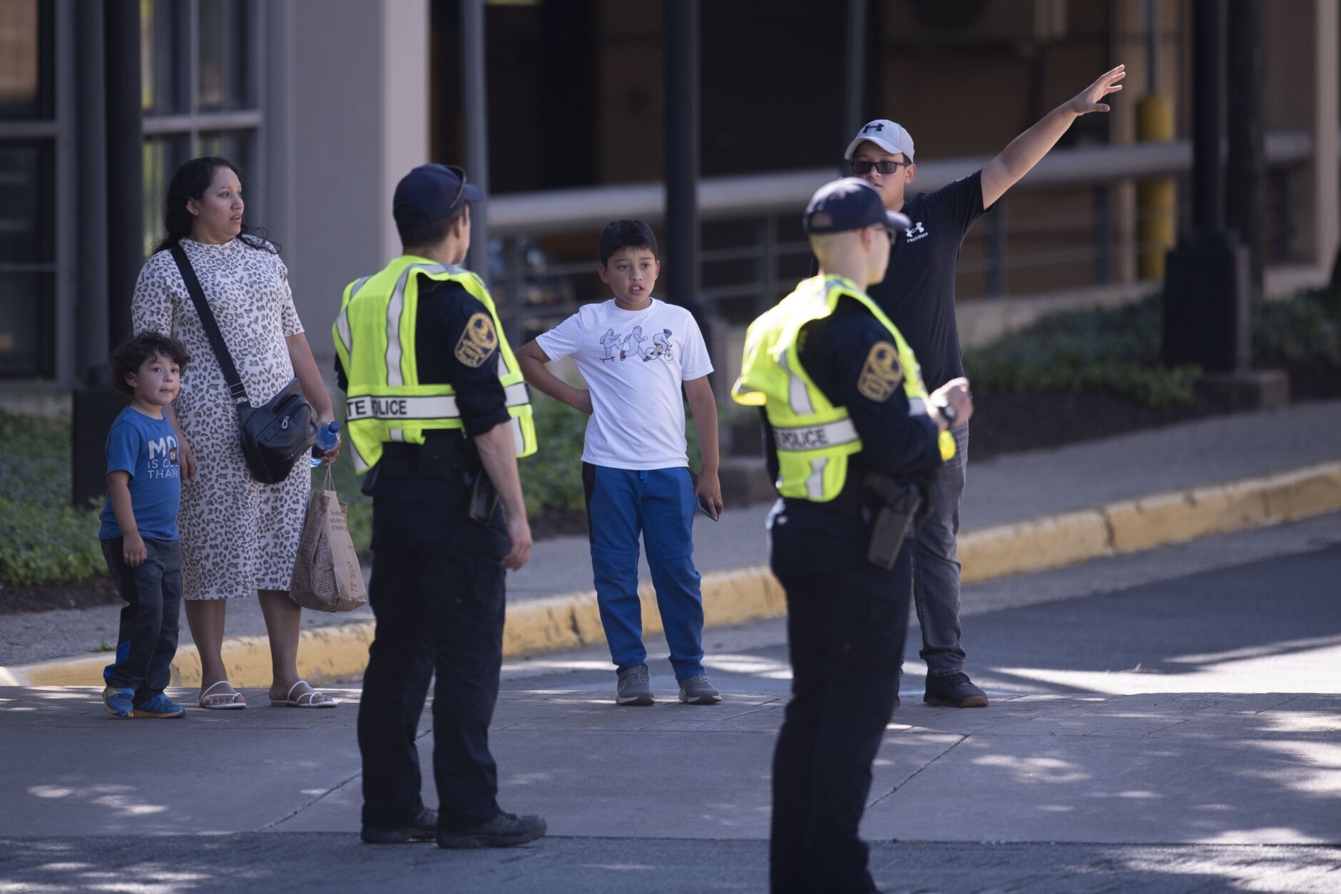 A family is advised by Virginia State Police on a direction to leave the Tysons Corner Center mall, following a shooting inside the shopping center, in Tysons Corner, Va., Saturday, June 18, 2022. (AP Photo/Cliff Owen)