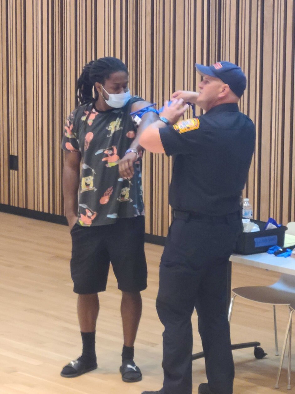 DC EMS Captain Charles Steptoe and an audience member demonstrate the proper use of a tourniquet to keep a shooting victim alive until first responders arrive. 