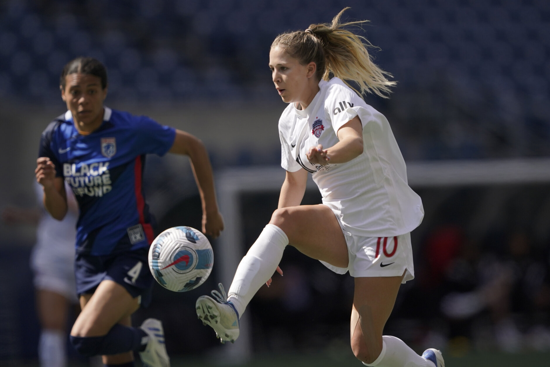 Washington Spirit forward Ashley Sanchez right, kicks the ball in front of OL Reign defender Alana Cook, left, during the first half of an NWSL soccer match, Sunday, May 22, 2022, in Seattle. (AP Photo/Ted S. Warren)