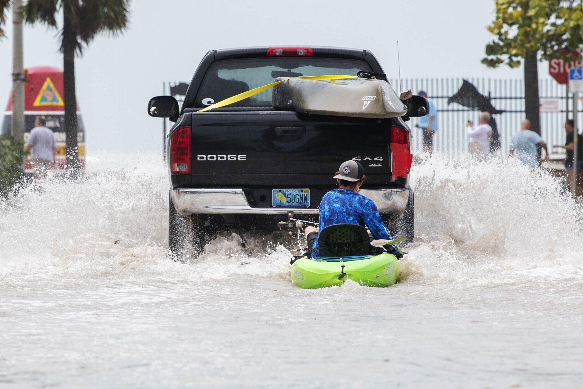 A truck pulls a man on a kayak on a low-lying road after flooding in the aftermath of Hurricane Ian, in Key West, Fla., Wednesday afternoon, Sept. 28, 2022. (AP Photo/Mary Martin)