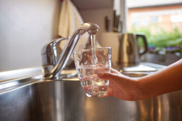 Tap water from a faucet filling a glass.