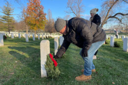A man lays a wreath on a headstone at Arlington National Cemetery during National Wreaths Across America Day on Dec. 17, 2022.