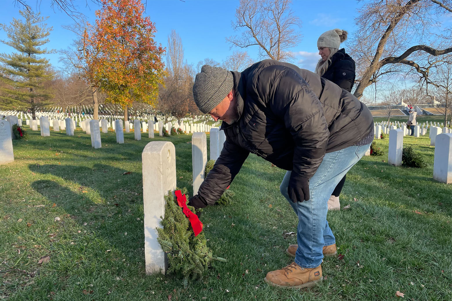 A man lays a wreath on a headstone at Arlington National Cemetery during National Wreaths Across America Day on Dec. 17, 2022.