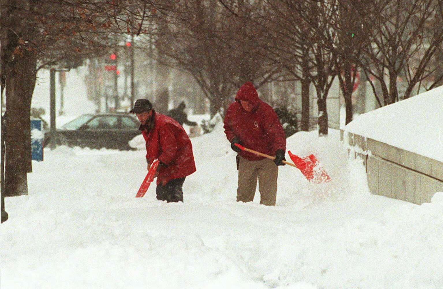 WASHINGTON, :  Two workers shovel snow from the sidewalks 08 January in downtown Washington, DC as snow continues to fall in one of the biggest snow storms to hit the area in recent history.  Forecasters predict a snow fall in excess of 30 inches in the area.   AFP  PHOTO    Bob PEARSON (Photo credit should read BOB PEARSON/AFP via Getty Images)