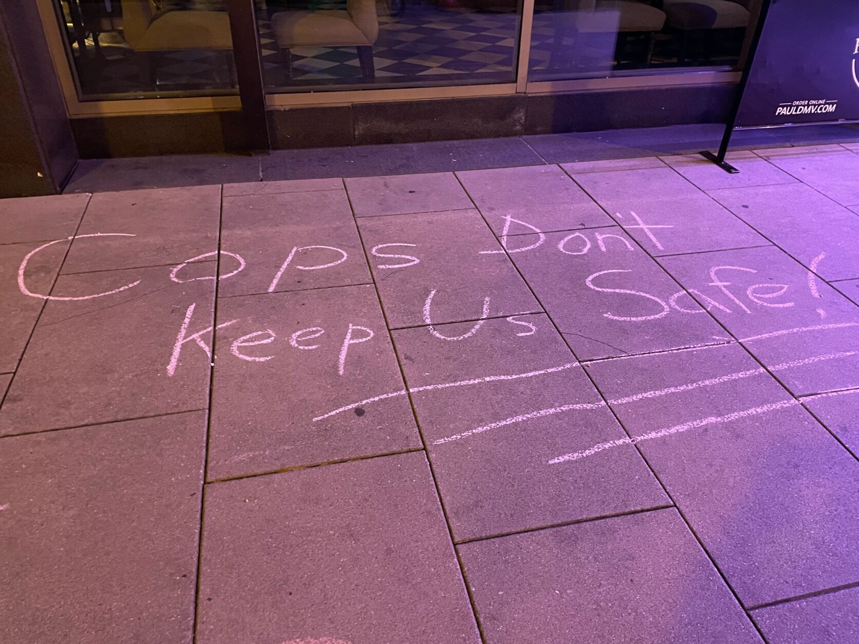 A sidewalk in downtown D.C. that reads "Cops don't keep us safe!"