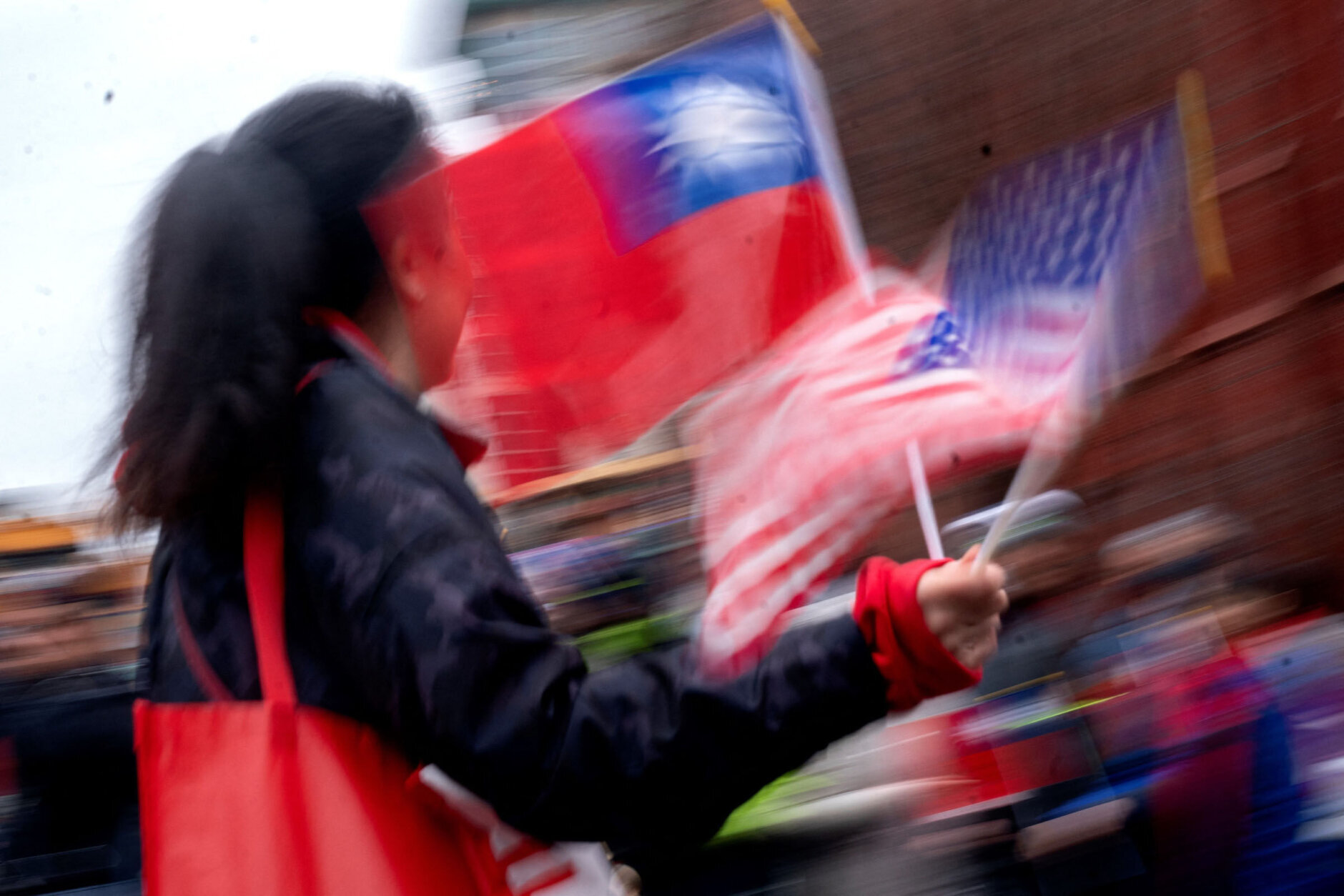 A participant waves flags from the US and Taiwan during the Lunar New Year Parade in the Chinatown neighborhood of Washington, DC, on January 22, 2023. - 2023 is the year of the rabbit in the Chinese horoscope. (Photo by Stefani Reynolds / AFP) (Photo by STEFANI REYNOLDS/AFP via Getty Images)