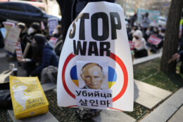 A protester holds a banner showing picture of Russian President Vladimir Putin during a rally to mark the one-year anniversary of Russia's invasion of Ukraine, in downtown Seoul, South Korea, Saturday, Feb. 25, 2023. (AP Photo/Lee Jin-man)