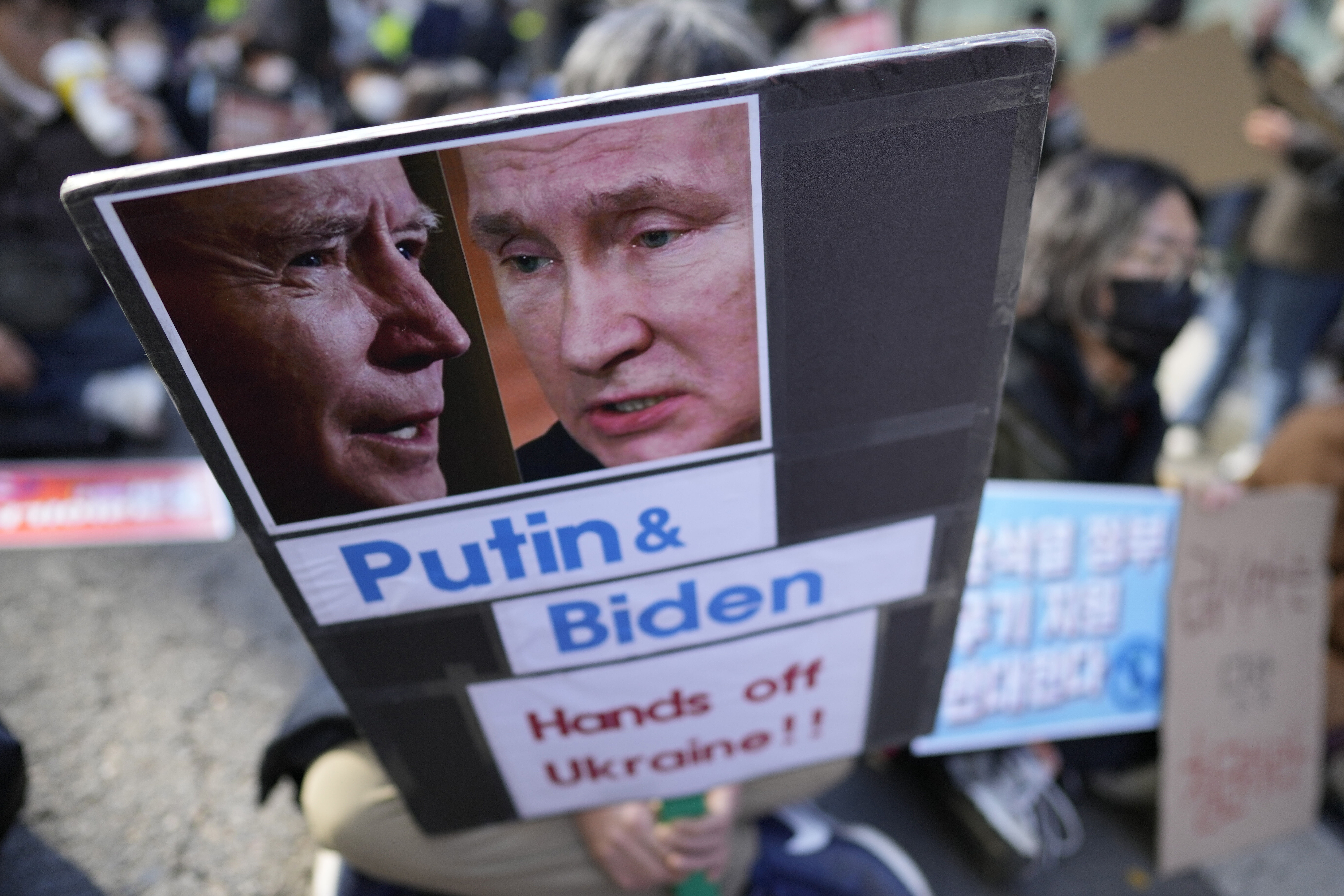 A protester holds a banner showing pictures of U.S. President Joe Biden, left, and Russian President Vladimir Putin during a rally to mark the one-year anniversary of Russia's invasion of Ukraine, in downtown Seoul, South Korea, Saturday, Feb. 25, 2023. (AP Photo/Lee Jin-man)