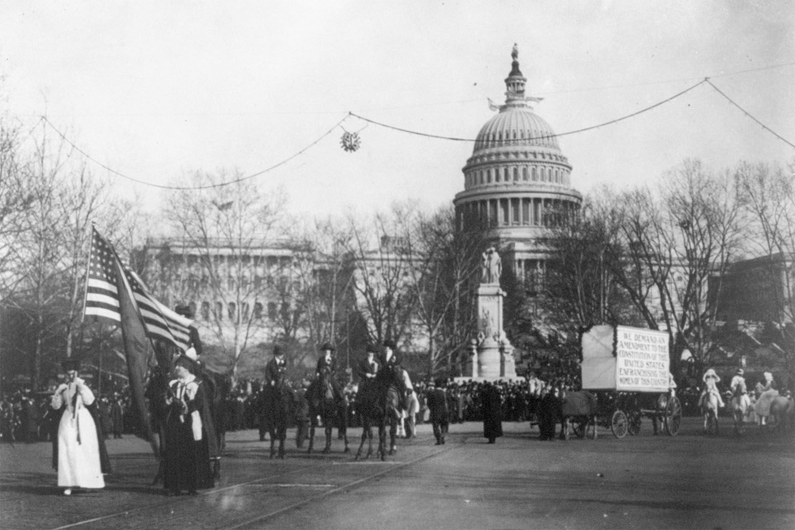 In this circa 1913 photo made available by the Library of Congress, demonstrators march in a women's suffrage parade near the Capitol building in Washington. A horse and cart pulls a sign which reads, "We demand an amendment to the constitution of the United States enfranchising the women of this country." (Harris &amp; Ewing/Library of Congress via AP)