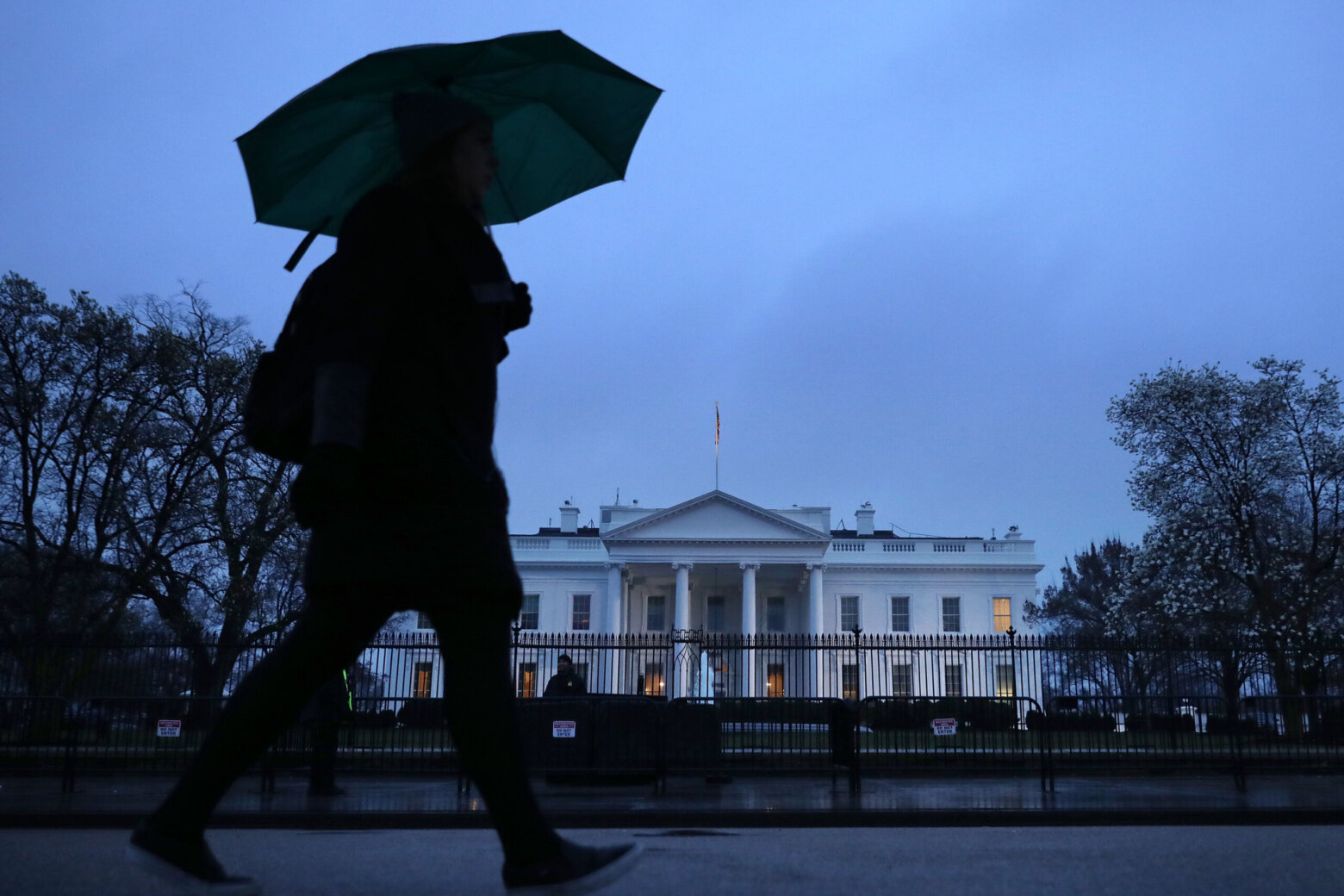 Person with umbrella walks by the White House