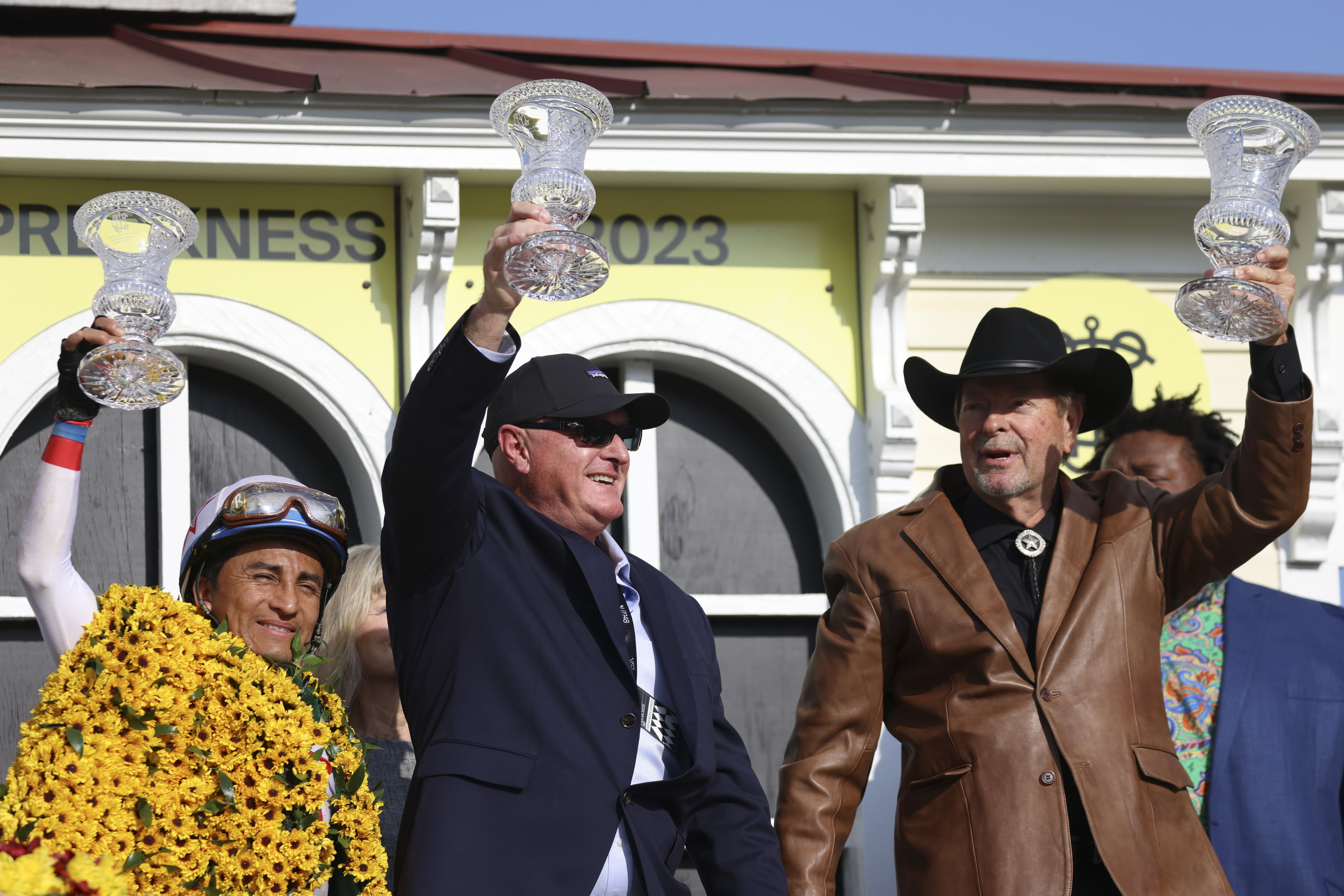 Rafael Bejarano, left, celebrates with trainer Randy Morse, center, and Richard Bahde, owner of Taxed, after winning the 98th running of the Black-Eyed Susan horse race at Pimlico Race Course, Friday, May 19, 2023, in Baltimore. (AP Photo/Julia Nikhinson)