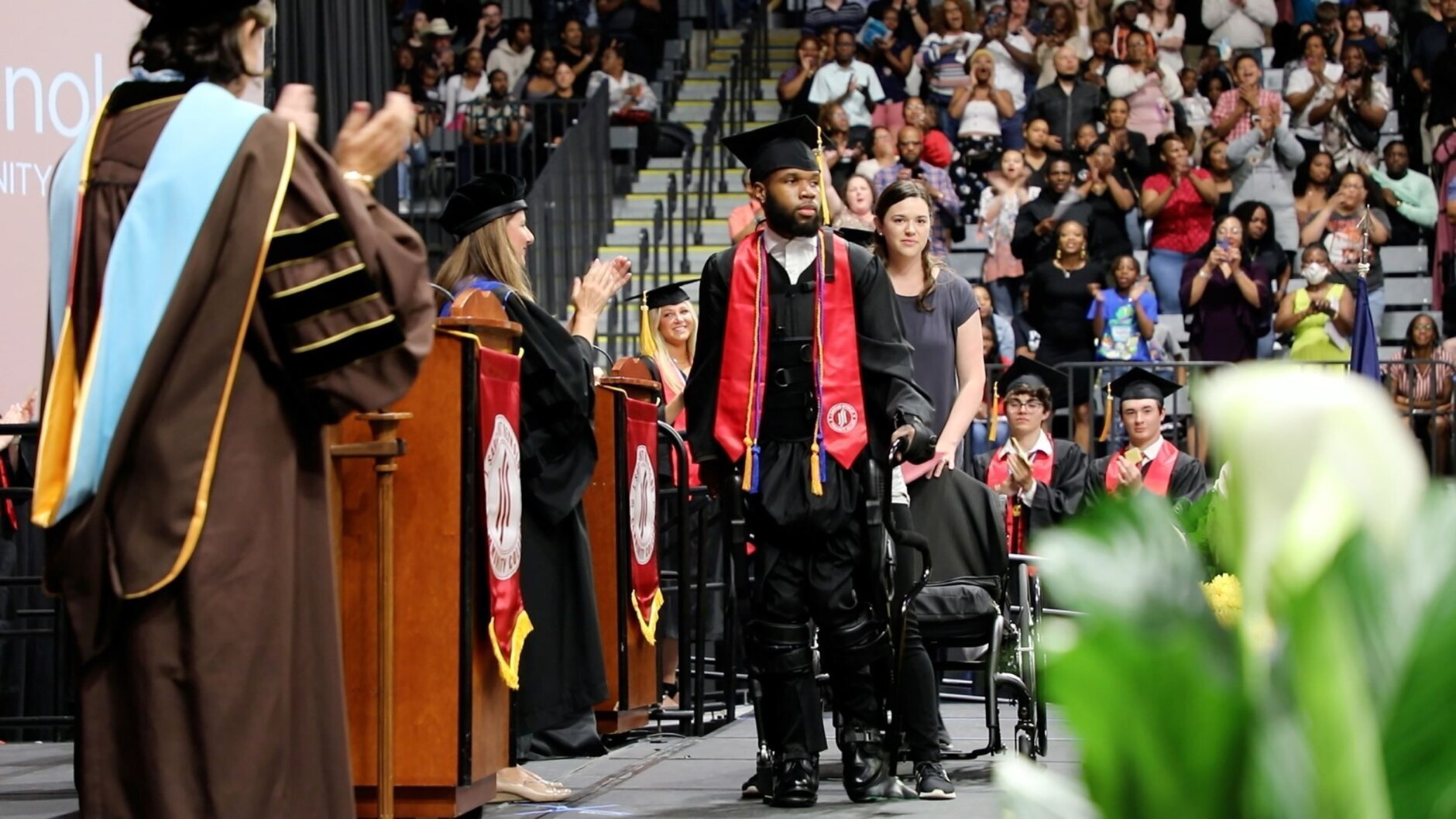 Khalil Watson uses an exoskeleton to stand and walk at his college graduation ceremony years after he was shot and paralyzed from the neck down.