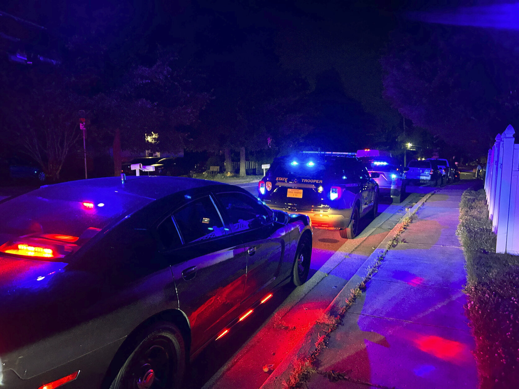 Police vehicles are seen on a residential street in Annapolis, Md., where police say multiple people were shot at a home on Sunday, June 11, 2023. (AP Photo/Brian Witte)