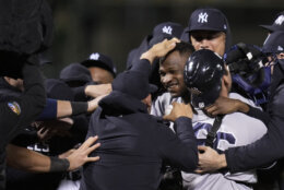 New York Yankees' Domingo Germán, with no hat hor helmet, is mobbed by teammates after he pitched a perfect game against the Oakland Athletics during a baseball game in Oakland, Calif., Wednesday, June 28, 2023. The Yankees won 11-0. (AP Photo/Godofredo A. Vásquez)