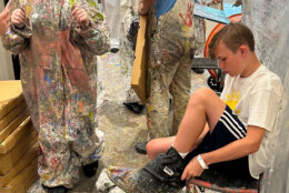 Participants don paint suits and then go to town on their canvases. (WTOP/Matt Kaufax)