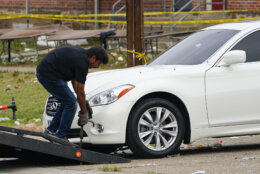 A tow truck operator removes a vehicle with multiple bullet holes near the area of a mass shooting incident in the Southern District of Baltimore, Sunday, July 2, 2023. Police say a number of people were killed and dozens were wounded in a mass shooting that took place during a block party just after midnight. (AP Photo/Julio Cortez)