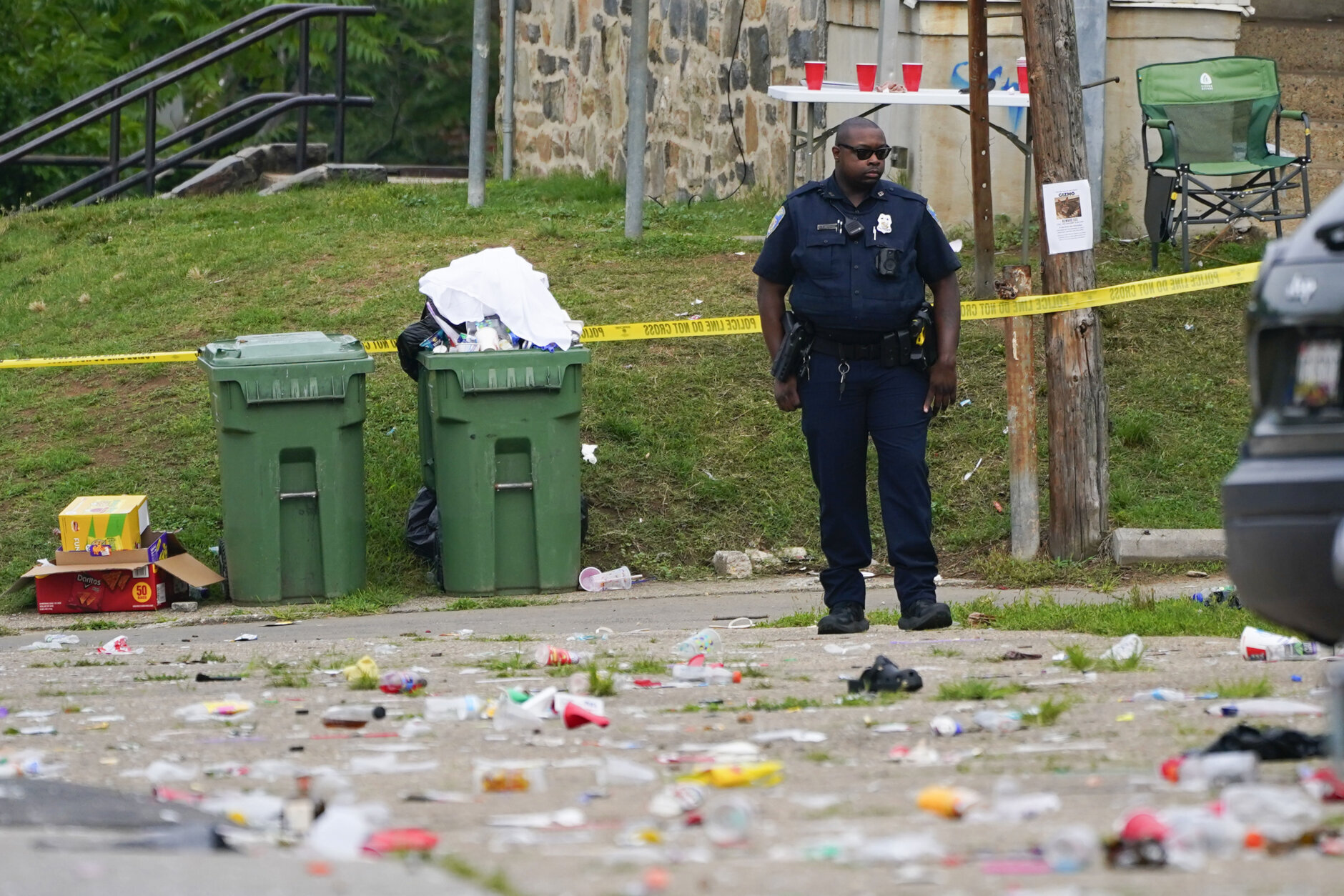 A police officer stands in the area of a mass shooting incident in the Southern District of Baltimore, Sunday, July 2, 2023. Police say a number of people were killed and dozens were wounded in a mass shooting that took place during a block party just after midnight. (AP Photo/Julio Cortez)