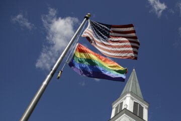 Gay Pride rainbow flag flies with the US flag