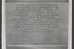 A black and white photograph of the Theoretical Physics Conference plaque, it contains the text "In this room, January 26, 1939, Niels Bohr made the first public announcement of the successful disintegration of uranium into barium with the attendant release of approximately two hundred million electron volts of energy per disintegration. (Courtesy of George Washington University)