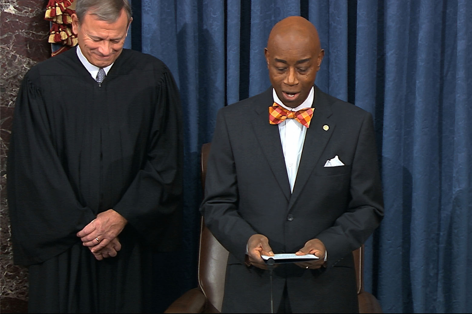 In this image from video, Chief Justice of the United States John Roberts smiles as Senate chaplain retired Navy Adm. Barry Black wishes him a happy birthday during the opening prayer during the impeachment trial against President Donald Trump in the Senate at the U.S. Capitol in Washington, Monday, Jan. 27, 2020. (Senate Television via AP)