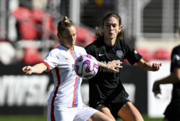 OL Reign midfielder Jess Fishlock and Washington Spirit midfielder Paige Metayer compete for the ball during the first half of an NWSL soccer match, Sunday, March 26, 2023, in Washington. (AP Photo/Terrance Williams)