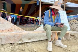 Willonius Hatcher, 39, comedian and screenwriter and AI content creator checks his phone at Black Rock City Burning man on September 3, 2023. Tens of thousands of festivalgoers were stranded September 3, in deep mud in the Nevada desert after rain turned the annual Burning Man gathering into a quagmire, with police investigating one death.
Video footage showed costume-wearing "burners" struggling across the wet gray-brown site, some using trash bags as makeshift boots, while many vehicles were stuck in the sludge. (Photo by Julie JAMMOT / AFP) (Photo by JULIE JAMMOT/AFP via Getty Images)