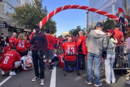 Fans donning red Capitals jersey line the street outside Capital One Arena ahead of the team's season opener.