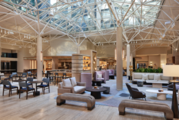 Seats are scattered around a hotel lobby with high ceilings and a glass roof